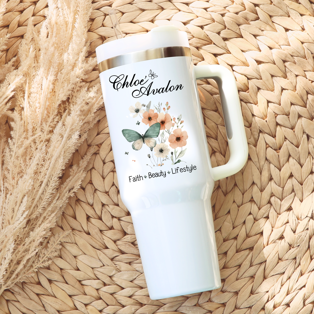 Chloé Avalon 40 oz tumbler in white with a silver rim, handle and clear straw, printed with the Chloé Avalon script logo, a watercolor butterfly with peach florals, and Faith · Beauty · Lifestyle