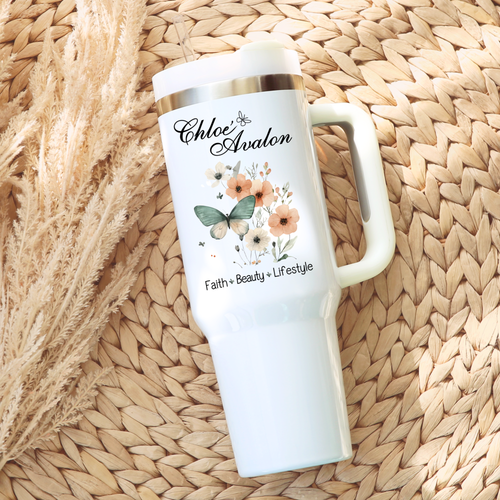 Chloé Avalon 40 oz tumbler in white with a silver rim, handle and clear straw, printed with the Chloé Avalon script logo, a watercolor butterfly with peach florals, and Faith · Beauty · Lifestyle